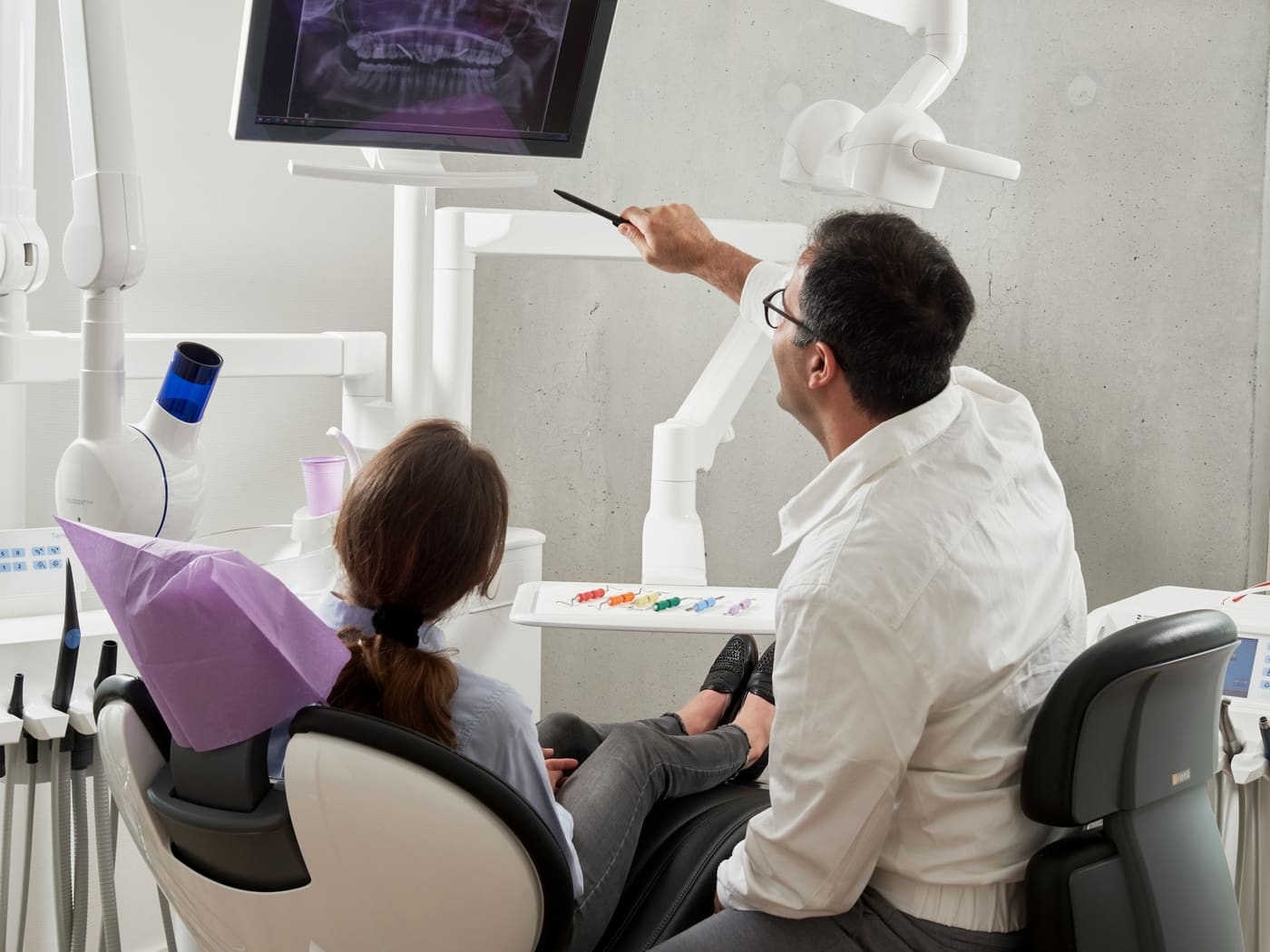 A dentist reviewing a dental X-ray on a monitor with a patient